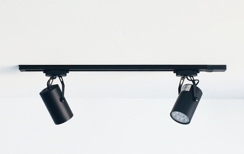 Two Black Track Lights Mounted To The Ceiling Positioned At Different Aangles