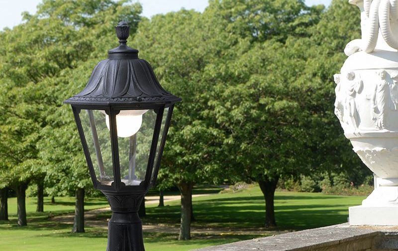 Outdoor small LED post Lantern in black mounted onto a wall in a garden