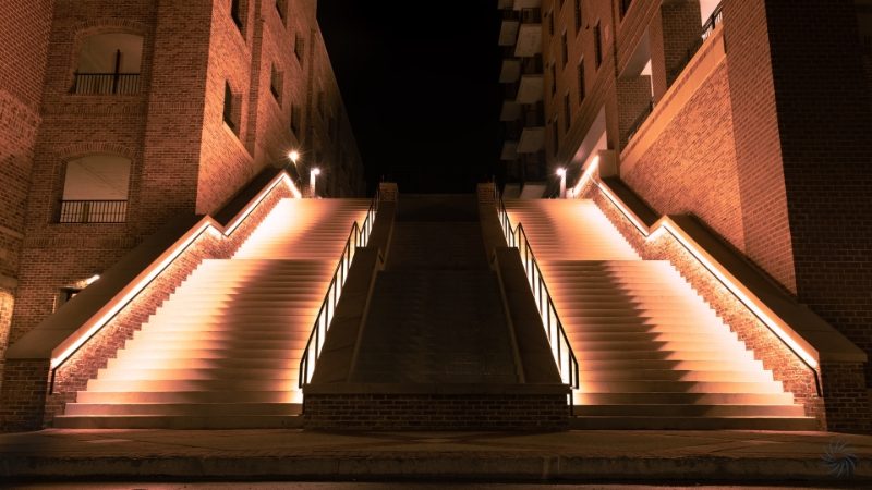 Two sets of modern red brick staircases outdoors with illuminated handrails