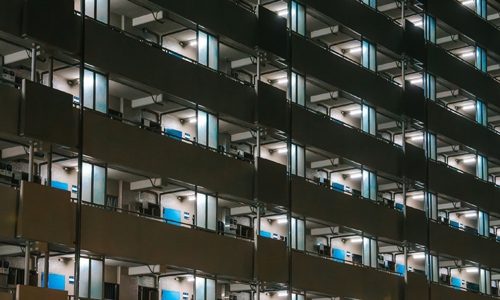 Apartment block with lots of balconies and fluorescent lighting switched on